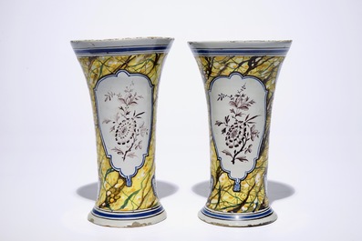 A pair of Dutch Delft polychrome beaker vases and two chargers, 18th C.