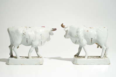 A pair of large cold-painted white Dutch Delft cows on bases, 18th C.