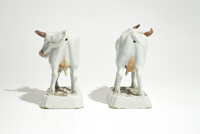 A pair of large cold-painted white Dutch Delft cows on bases, 18th C.