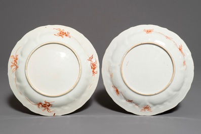 A pair of Chinese iron red and gilt plates with figures in a garden, Kangxi