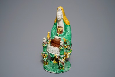 A Chinese verte biscuit group of Guanyin on a lotus throne, 18th C.