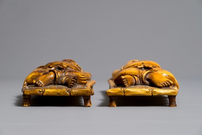 A pair of Chinese carved ivory figures of resting men on a bed, 19th C.