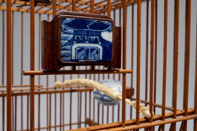 Een Chinese houten vogelkooi met ivoren en porseleinen ornamenten, 19/20e eeuw