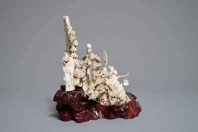 A Chinese ivory group of figures in a landscape on carved wooden base, 1st half 20th C.