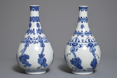 A pair of Chinese blue and white bottle vases with ribbons and precious objects, Kangxi