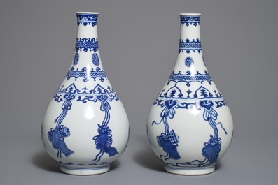 A pair of Chinese blue and white bottle vases with ribbons and precious objects, Kangxi