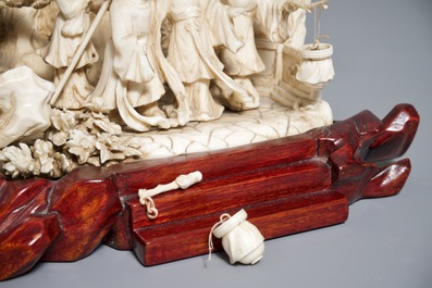 A Chinese ivory group of figures in a landscape on carved wooden base, 1st half 20th C.