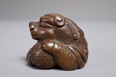 A Chinese bronze scroll or paper weight shaped as a Buddhist lion or Shishi with a ball, 17/18th C.