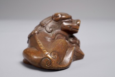 A Chinese bronze scroll or paper weight shaped as a Buddhist lion or Shishi with a ball, 17/18th C.