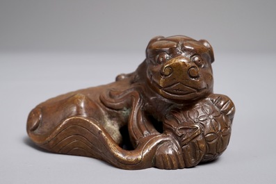 Een Chinees bronzen scroll- of papiergewicht in de vorm van een Boeddhistische leeuw of Shishi met bal, 17/18e eeuw