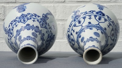 A pair of Chinese blue and white bottle vases with ribbons and precious objects, Kangxi