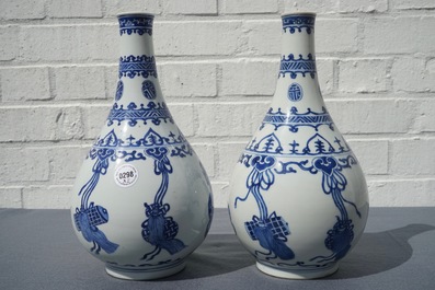 A pair of Chinese blue and white bottle vases with ribbons and precious objects, Kangxi