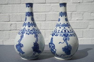 A pair of Chinese blue and white bottle vases with ribbons and precious objects, Kangxi