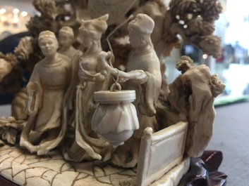 A Chinese ivory group of figures in a landscape on carved wooden base, 1st half 20th C.