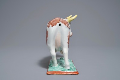 A polychrome Dutch Delft petit feu cow on base, 18th C.