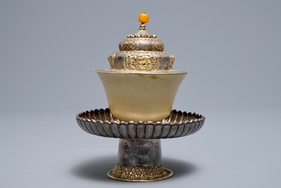 A Tibetan ritual jade bowl on parcel-gilt silver stand with amber finial, 19th C