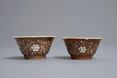 Une paire de tasses et soucoupes en porcelaine de Chine bleu et blanc &agrave; d&eacute;cor grav&eacute; sur fond brun capucin, Kangxi