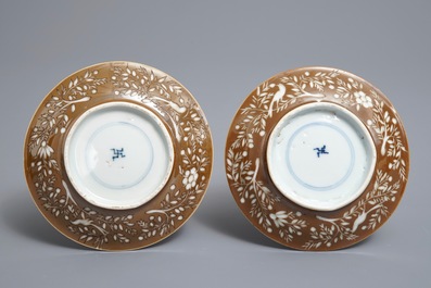 Une paire de tasses et soucoupes en porcelaine de Chine bleu et blanc &agrave; d&eacute;cor grav&eacute; sur fond brun capucin, Kangxi