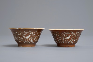 Une paire de tasses et soucoupes en porcelaine de Chine bleu et blanc &agrave; d&eacute;cor grav&eacute; sur fond brun capucin, Kangxi