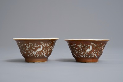 Une paire de tasses et soucoupes en porcelaine de Chine bleu et blanc &agrave; d&eacute;cor grav&eacute; sur fond brun capucin, Kangxi