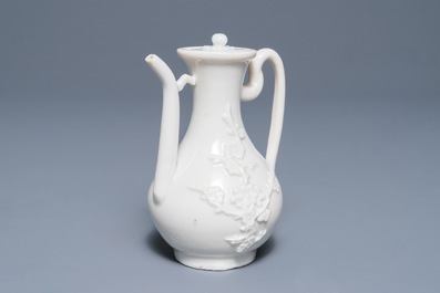 A Chinese Dehua blanc de Chine wine jug and cover with applied floral design, Kangxi