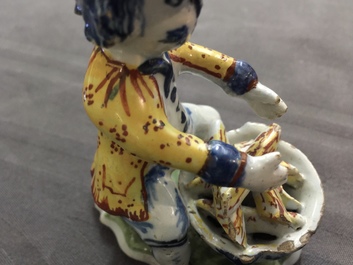 A polychrome Dutch Delft model of a man near a stove, 18th C.