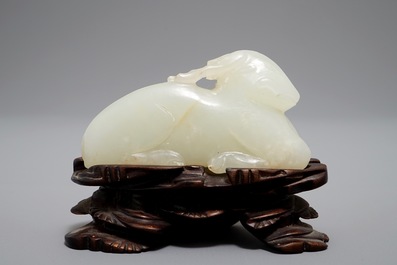 A Chinese jade carving of a ram on wooden base, 19th C.