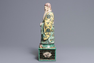 A large Chinese verte biscuit figure of an immortal on reticulated stand, Kangxi