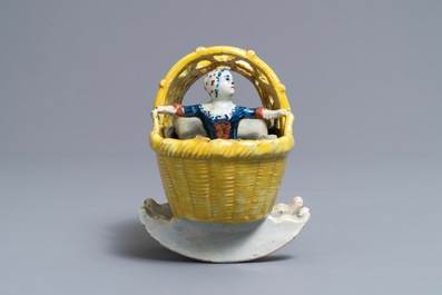 A polychrome Dutch Delft model of a girl in a cradle, 18th C.