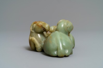 A Chinese pale celadon and russet jade 'three rams' group on carved wooden stand, 18/19th C.