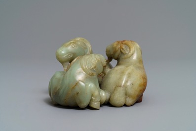 A Chinese pale celadon and russet jade 'three rams' group on carved wooden stand, 18/19th C.