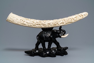 Une d&eacute;fense d'ivoire sculpt&eacute;e sur socle en bois en forme d'&eacute;l&eacute;phant, Chine, vers 1900