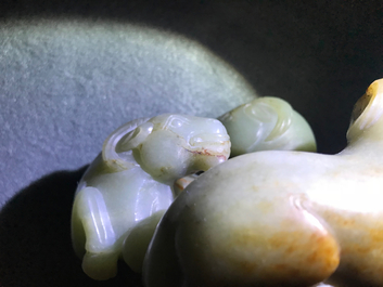 A Chinese pale celadon and russet jade 'three rams' group on carved wooden stand, 18/19th C.