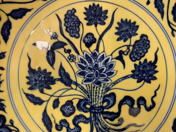 Een Chinees bord met blauwwit boeket van lotusbloemen op gele fondkleur, Qianlong merk, 19/20e eeuw