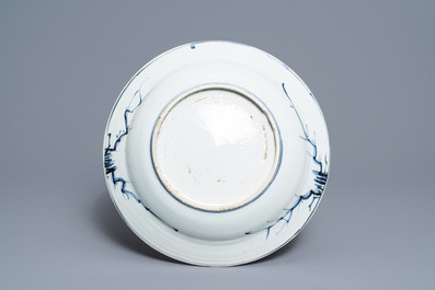 Un plat en porcelaine de Chine bleu et blanc &agrave; d&eacute;cor de figures dans un paysage, &eacute;poque Transition