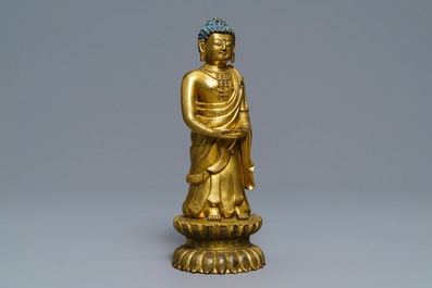 Een Chinese verguld bronzen figuur van een staande Boeddha met inscriptie, Qianlong