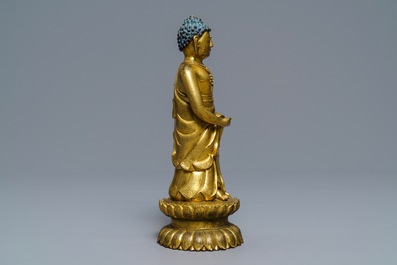 Een Chinese verguld bronzen figuur van een staande Boeddha met inscriptie, Qianlong