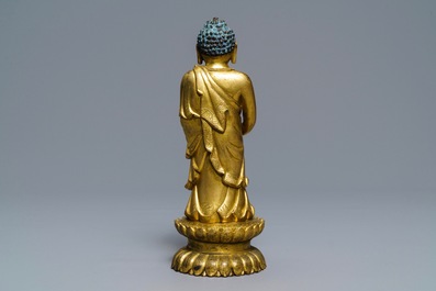 Een Chinese verguld bronzen figuur van een staande Boeddha met inscriptie, Qianlong