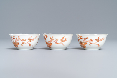 Three Chinese iron red eggshell cups and saucers with boys and goats, Yongzheng