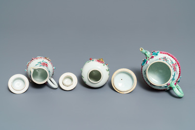 A Chinese famille rose relief-decorated teapot, milk jug and tea caddy on stands, Yongzheng