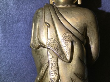 Een Chinese verguld bronzen figuur van een staande Boeddha met inscriptie, Qianlong