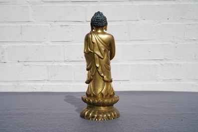 Een Chinese verguld bronzen figuur van een staande Boeddha met inscriptie, Qianlong