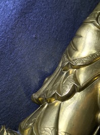 Een Chinese verguld bronzen figuur van een staande Boeddha met inscriptie, Qianlong