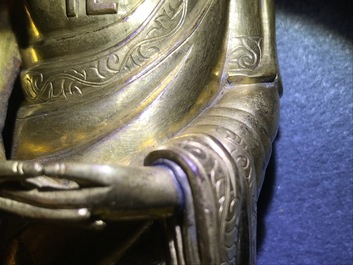 Een Chinese verguld bronzen figuur van een staande Boeddha met inscriptie, Qianlong