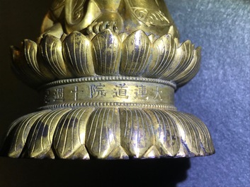 Een Chinese verguld bronzen figuur van een staande Boeddha met inscriptie, Qianlong