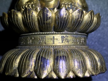 Een Chinese verguld bronzen figuur van een staande Boeddha met inscriptie, Qianlong