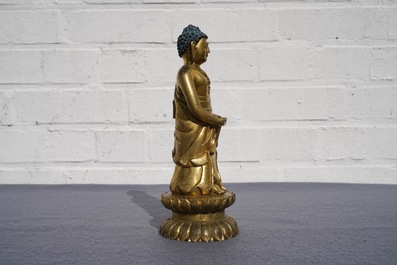 Een Chinese verguld bronzen figuur van een staande Boeddha met inscriptie, Qianlong