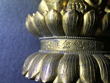 Een Chinese verguld bronzen figuur van een staande Boeddha met inscriptie, Qianlong