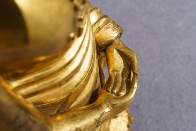 Een Chinese verguld bronzen figuur van een staande Boeddha met inscriptie, Qianlong