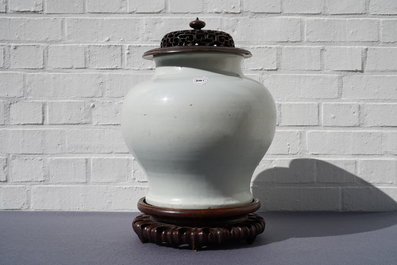 A Chinese monochrome white vase with a wooden cover and stand, Ming